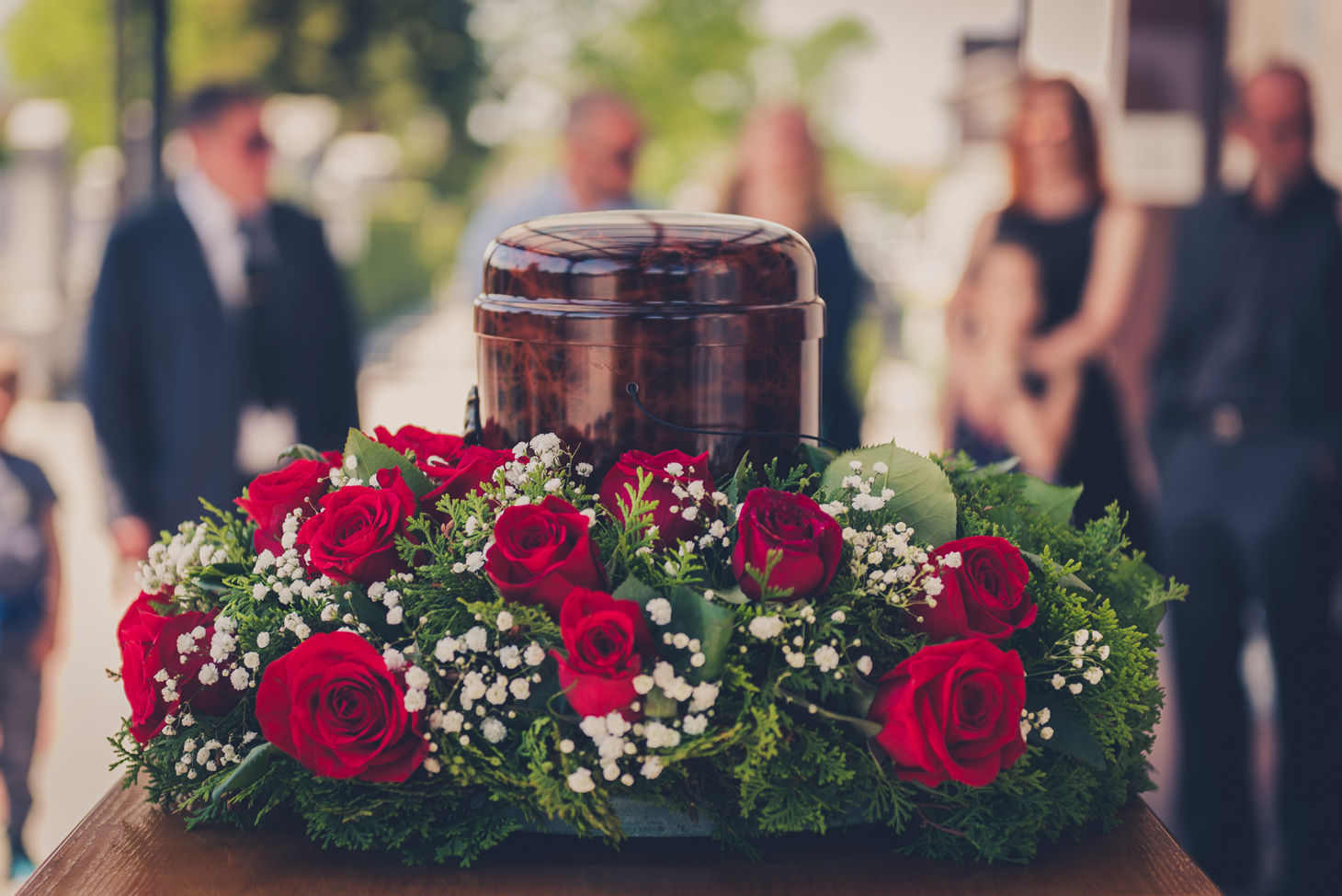 Eine Urne steht bei der Beerdigung auf einem Tisch mit Blumen.